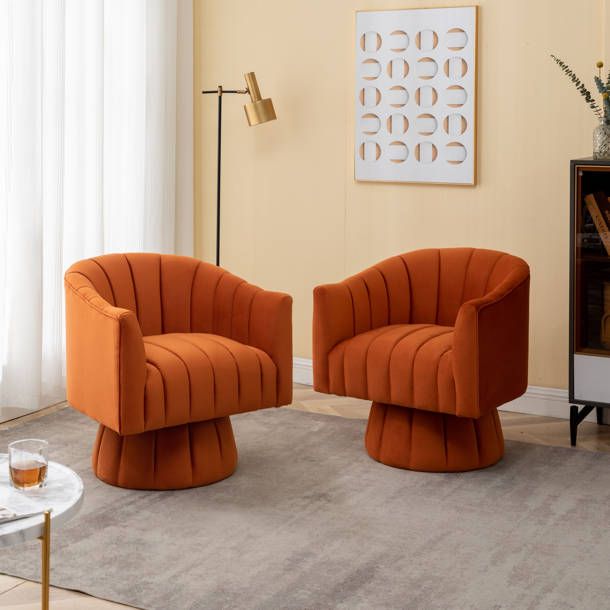 two orange chairs in a living room with a coffee table and lamp on the side