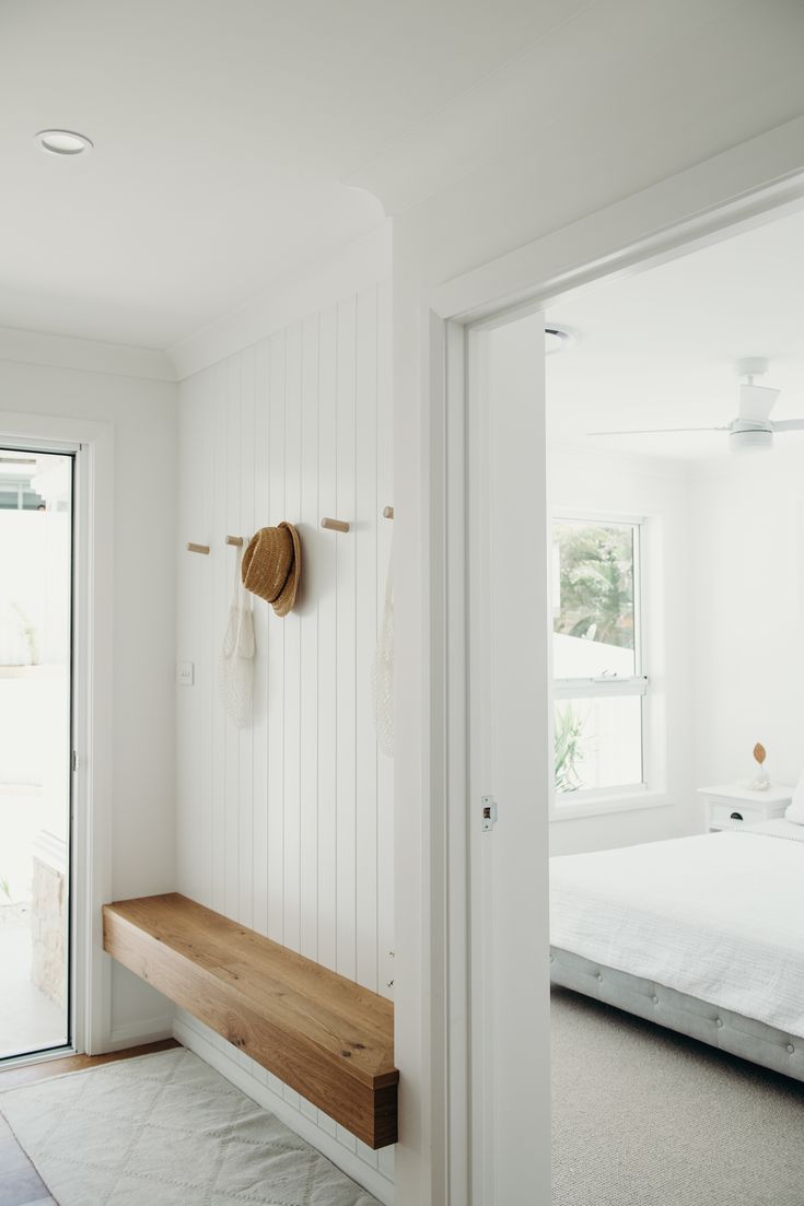 a bedroom with white walls and wooden bench