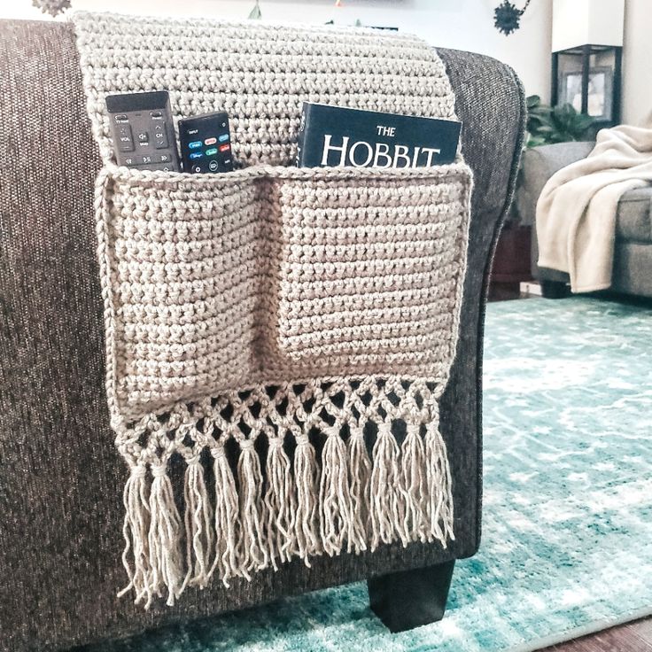 a crocheted book holder on a couch with a remote control in the pocket