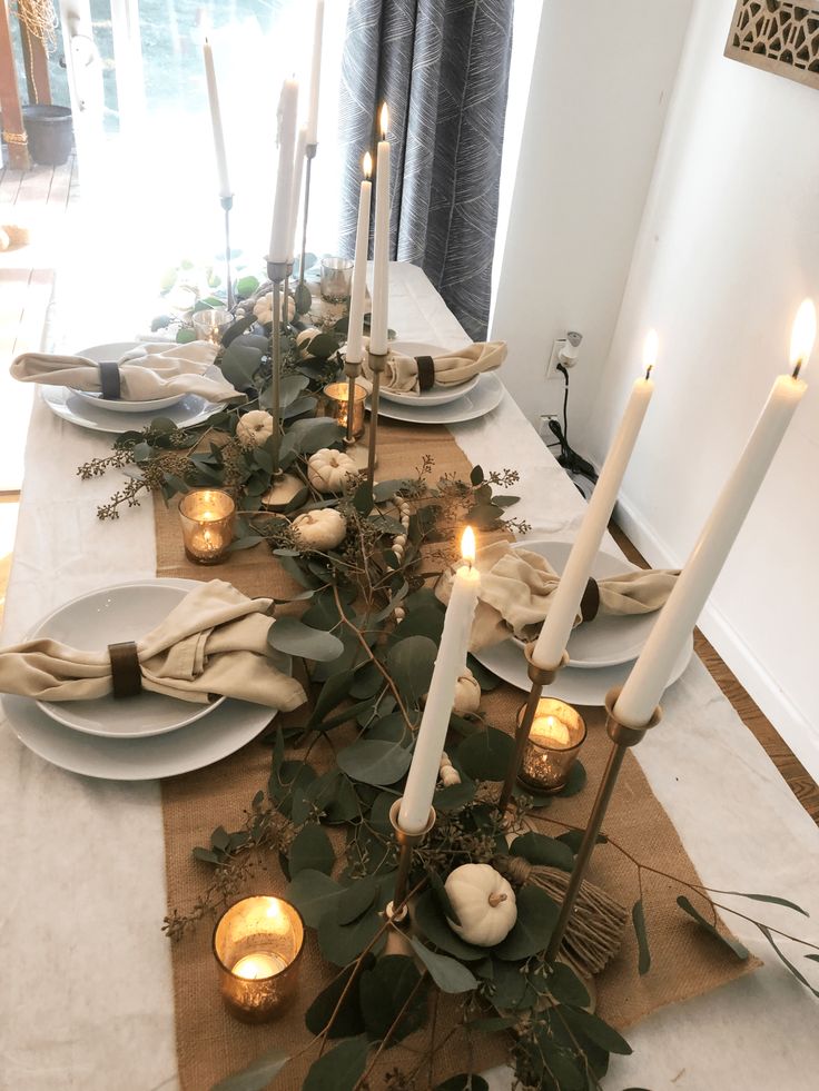 the table is set with candles and greenery