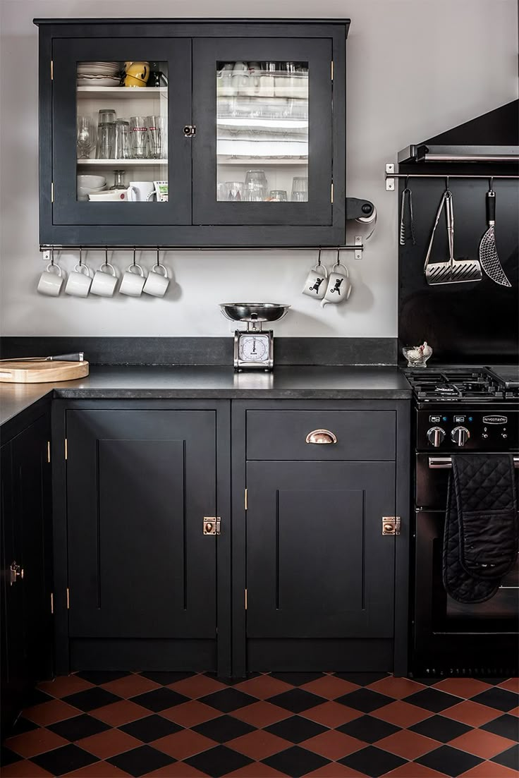 a black and white kitchen with checkered flooring on the floor, cabinet doors open to reveal utensils