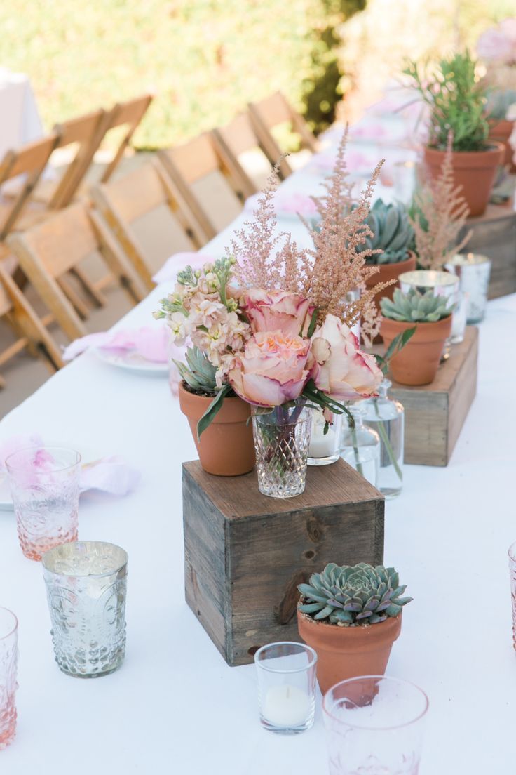 the table is set with succulents, candles and vases on it