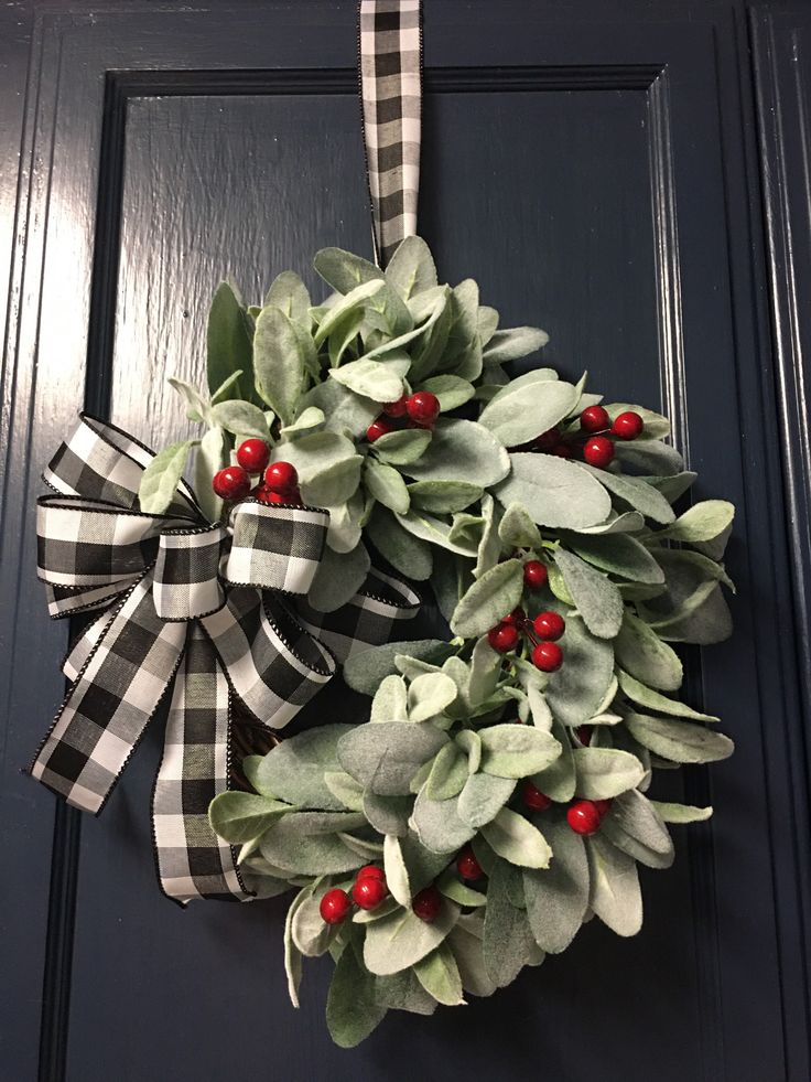 a wreath hanging on the front door decorated with holly and red berries is ready to be hung