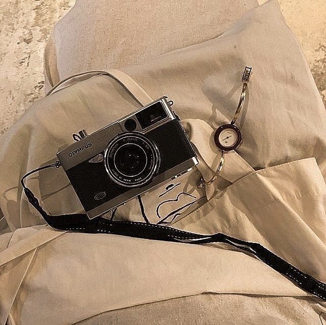 an old camera is laying on top of a white sheet with a cord attached to it