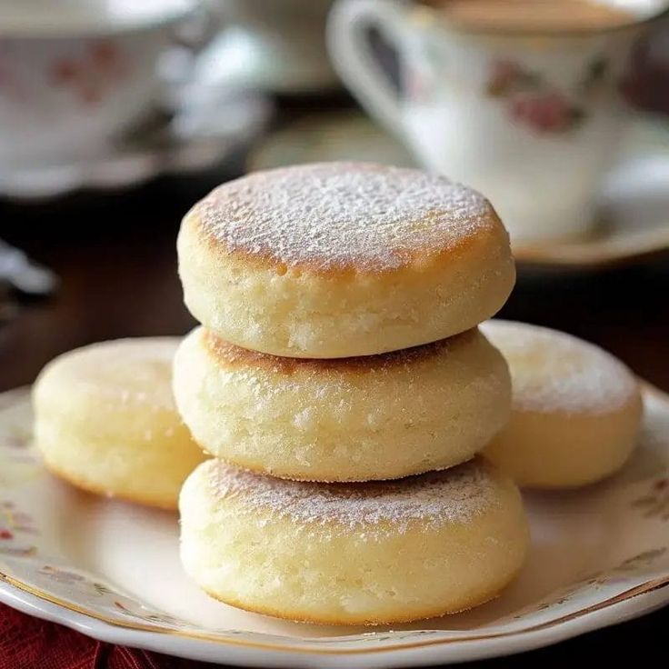 three sugar cookies stacked on top of each other in front of a cup and saucer