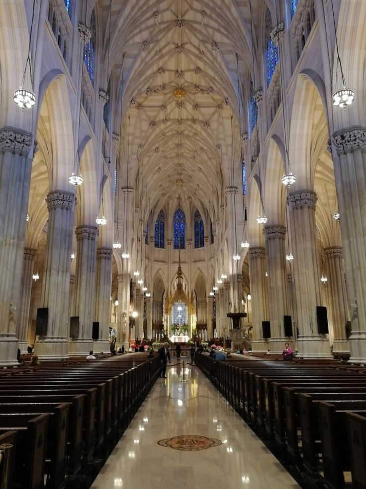 the inside of a large cathedral with pews and chandeliers on either side