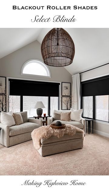 a living room with black roller shades and white couches in front of large windows