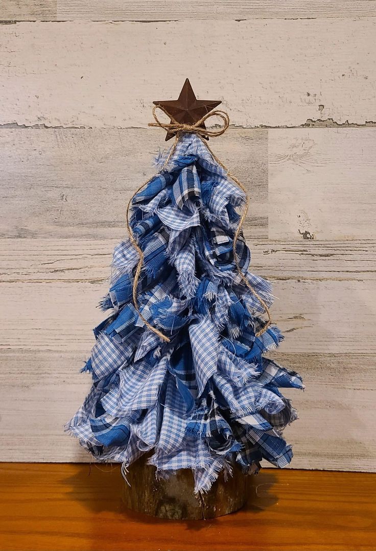 a blue and white plaid christmas tree with a star on top, sitting on a wooden table