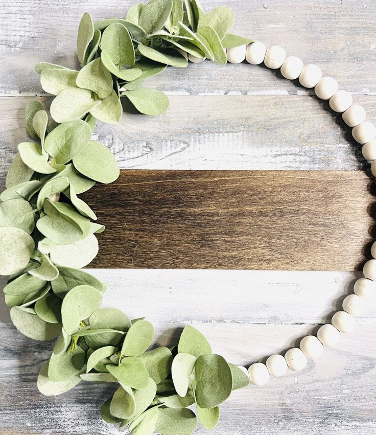 a wooden board with white beads and green leaves