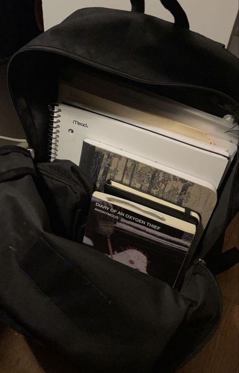 a black backpack filled with books on top of a wooden table