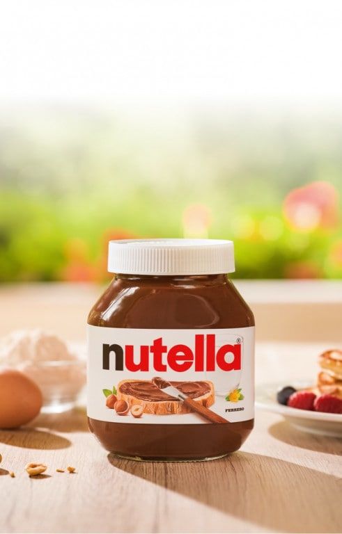 a jar of nutella sitting on top of a table next to eggs and fruit