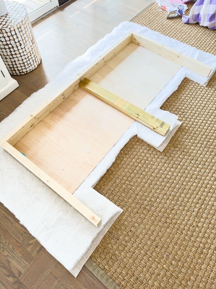 an unfinished tray is sitting on the floor next to some other pieces of wood and fabric