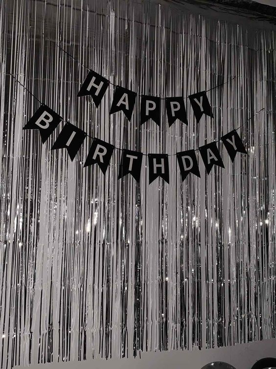 a black and white photo of a happy birthday banner with streamers hanging from the ceiling