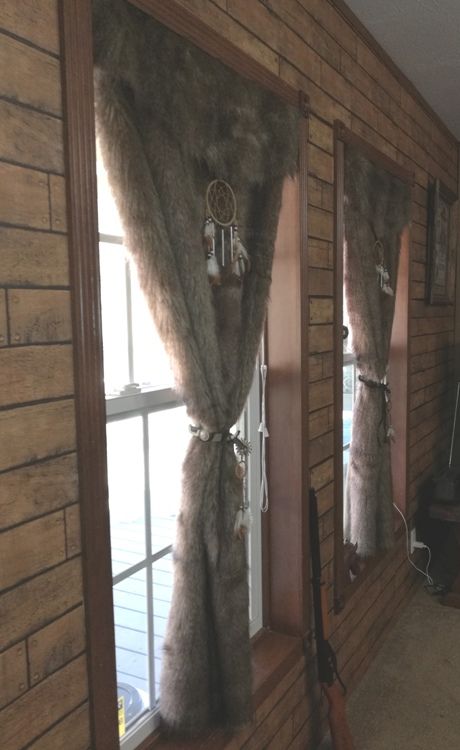 a room with wooden walls and windows decorated in faux furs, along with a guitar