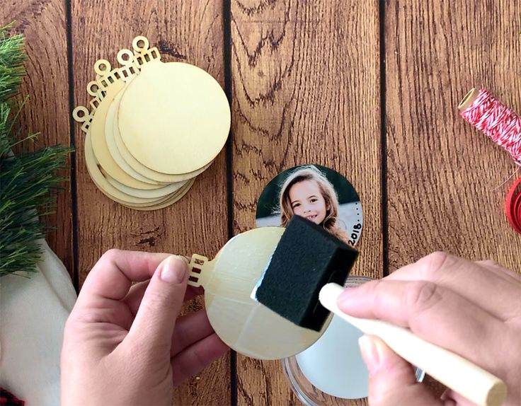 a person is holding a christmas ornament with a photo on it next to other ornaments