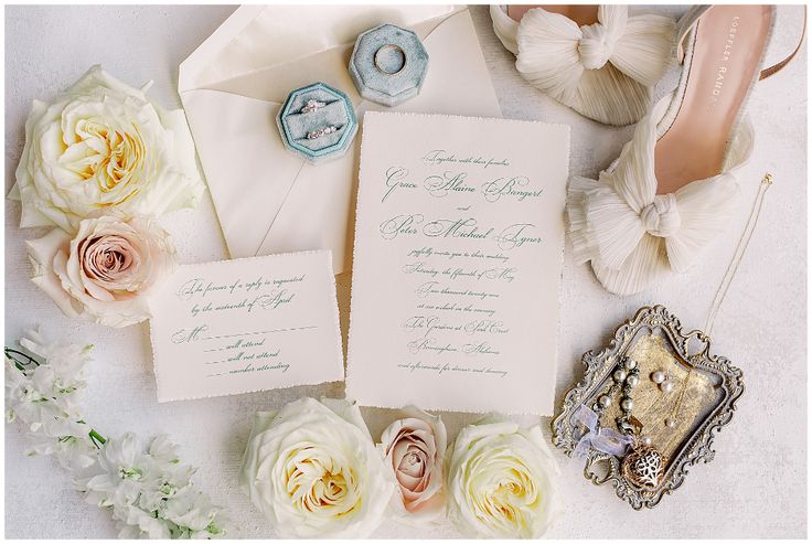 the wedding stationery is laid out on top of the table with shoes and flowers