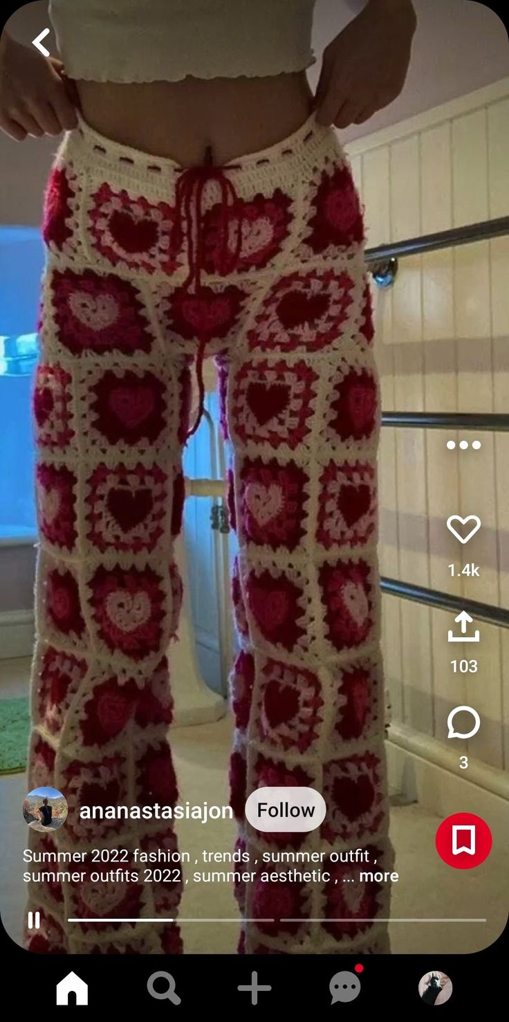 a woman wearing red and white crocheted pants with hearts on the bottom, in front of a mirror