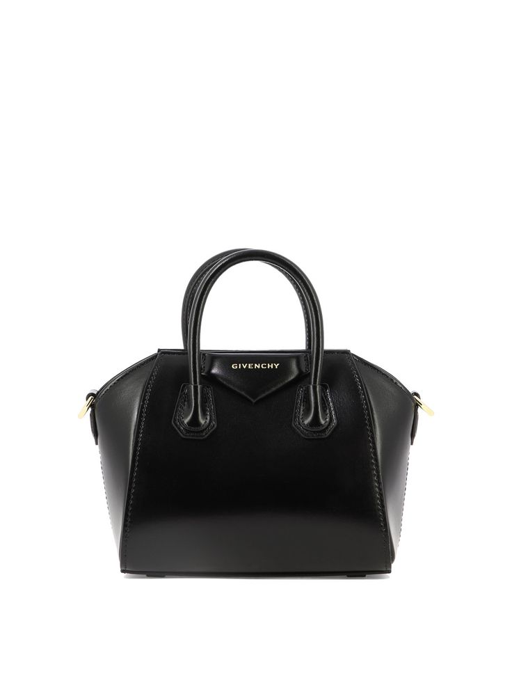 Givenchy's "Antigona Toy" handbag is the accessory for the sophisticated woman who seeks style and functionality. Made of two-tone leather with gold metallic details, this bag embodies elegance and practicality in one versatile product. || - Dimensions: 22x17.5x10 cm - Large removable shoulder strap in two-tone leather with GIVENCHY signature embossed on the top and 4G logos on the ends - Magnetic closure - Pentagonal application with embossed GIVENCHY signature - Gold-finish metallic details - Luxury Black Bags With Multiple Pockets, Luxury Shoulder Bag With Designer Logo, Luxury Black Bags With Designer Logo, Luxury Leather Shoulder Bag With Designer Logo, Luxury Black Bag With Logo Strap, Luxury Black Bag With Multiple Pockets, Luxury Women's Shoulder Bag For Night Out, Luxury Black Embellished Shoulder Bag, Luxury Black Shoulder Bag With Multiple Pockets