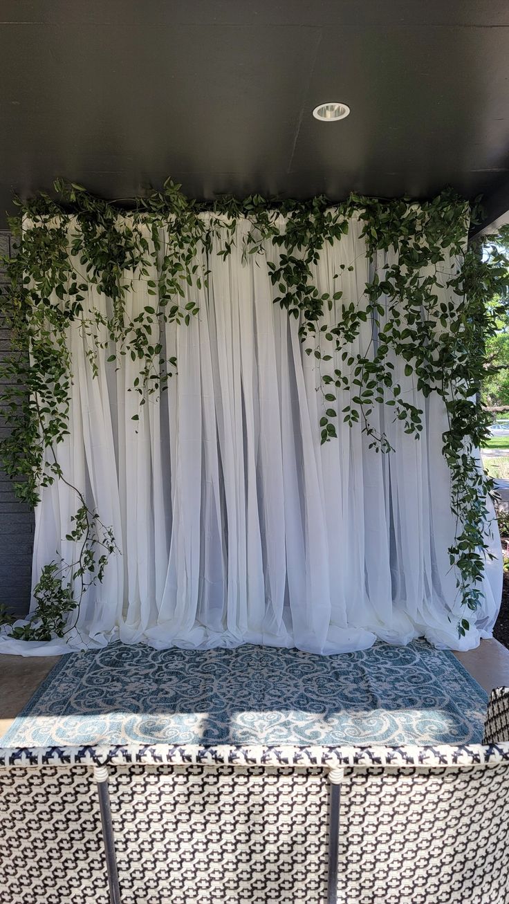 an outdoor stage with white drapes and vines on it