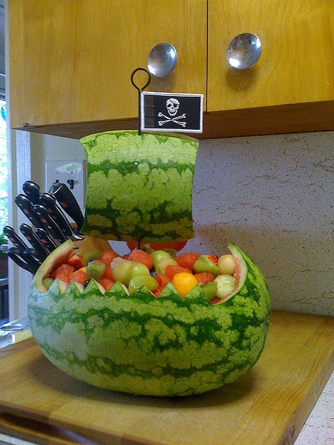 a large watermelon bowl filled with different types of fruits and vegetables on top of a counter