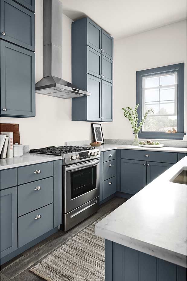 a kitchen with blue cabinets and stainless steel appliances, including an oven hood over the range