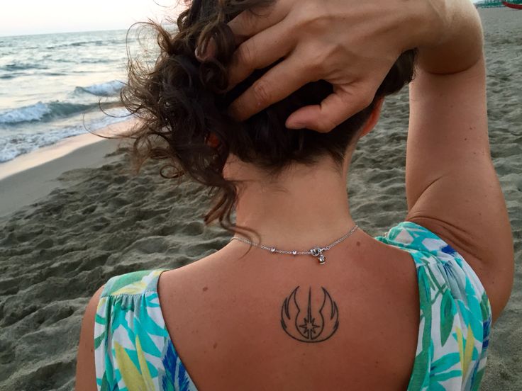 a woman with a star wars tattoo on her back is standing in front of the ocean