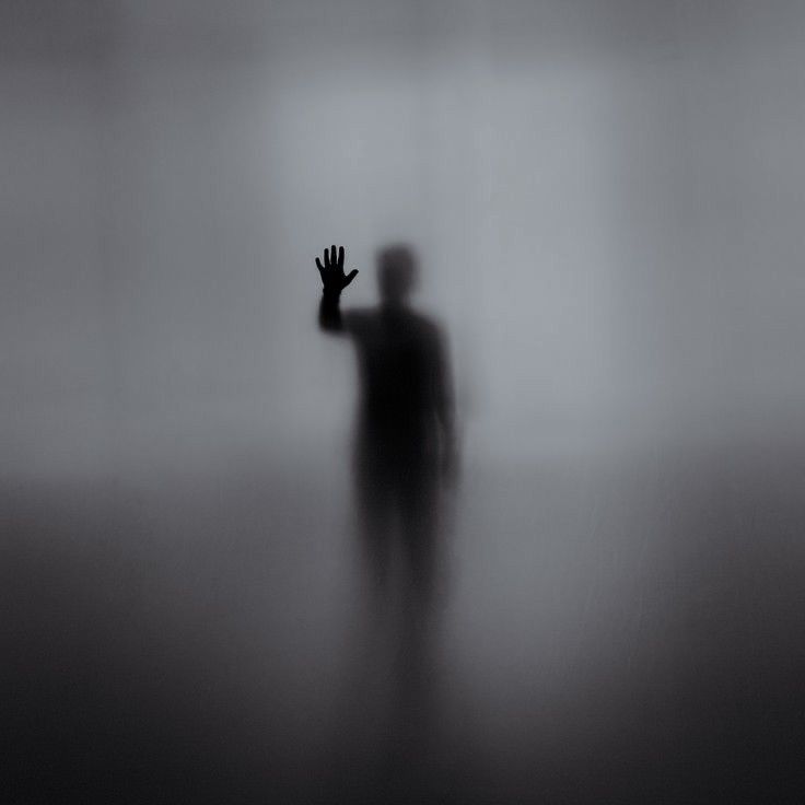 a person standing in the fog with their hand up