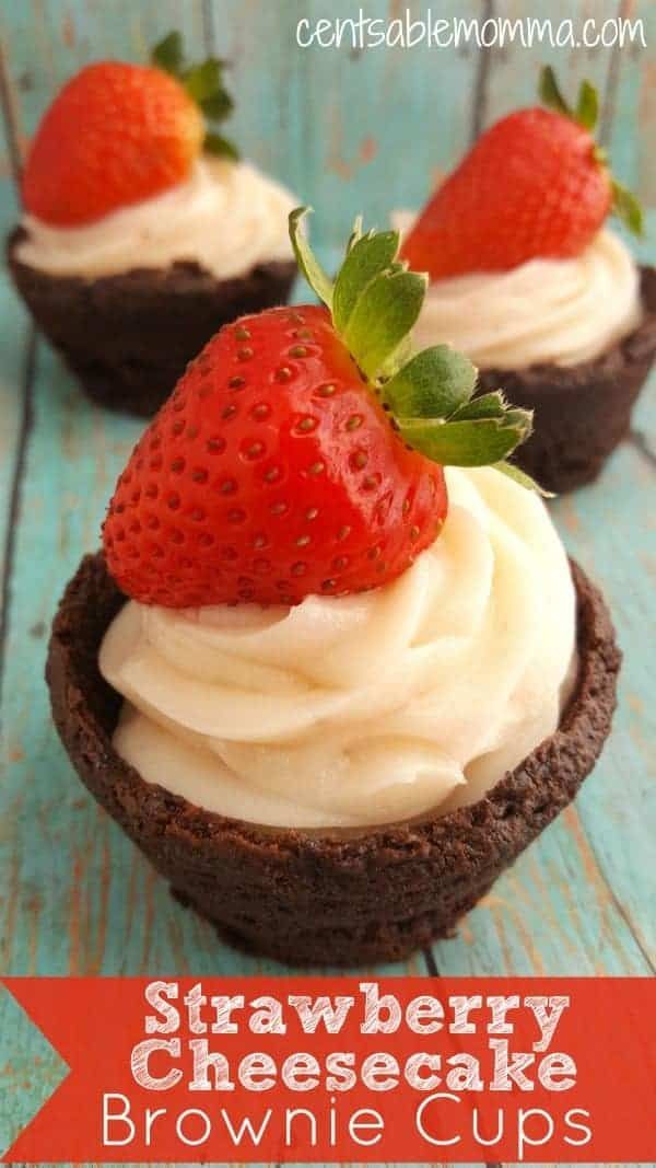 two chocolate cupcakes with cream frosting and strawberries on top, sitting on a blue wooden table