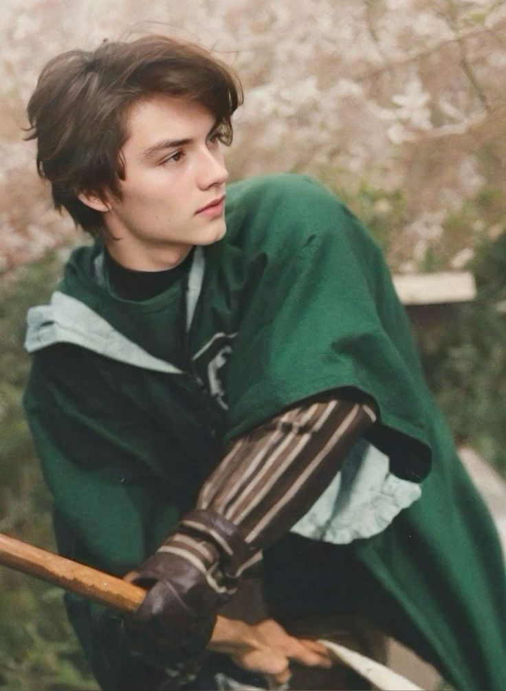 a young man dressed in medieval clothing holding a wooden stick