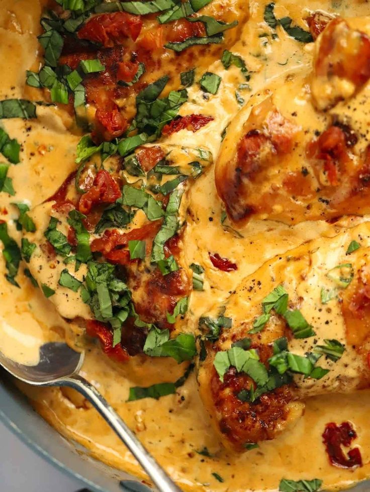 a pan filled with chicken covered in sauce and garnished with parsley