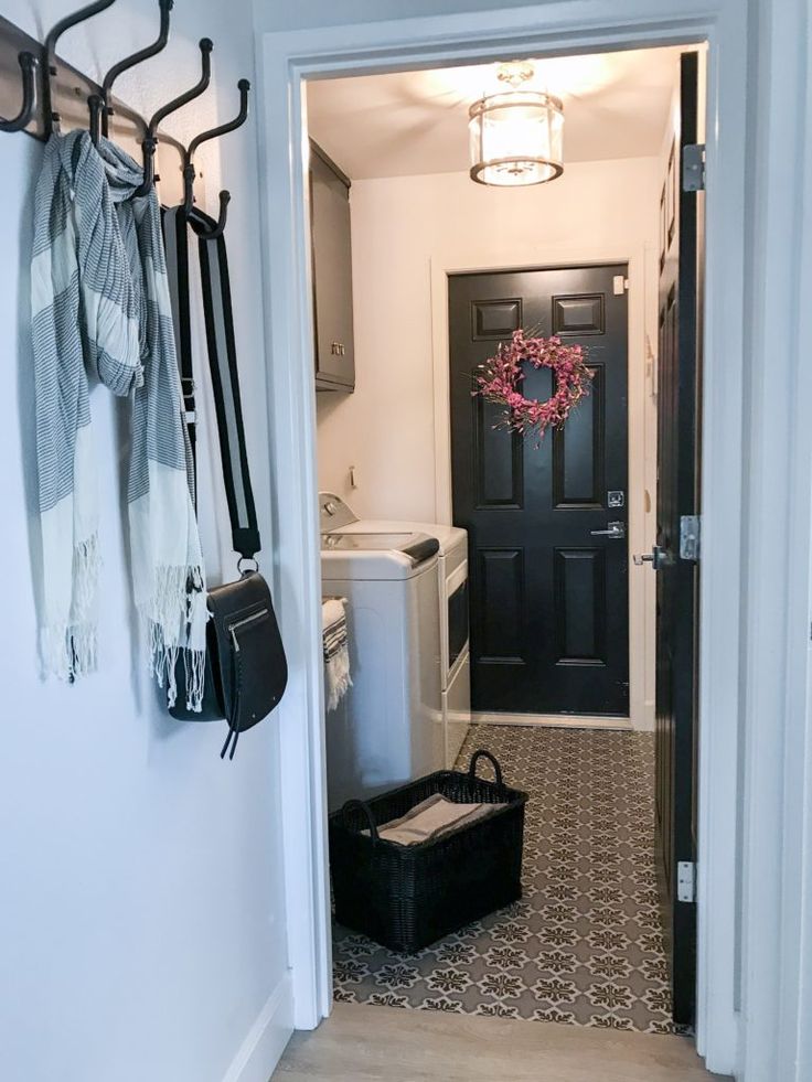 the entry way to a home with black doors and white walls, including a laundry hamper