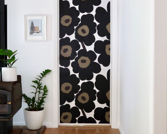 a black and white door with flowers painted on the wall next to potted plants