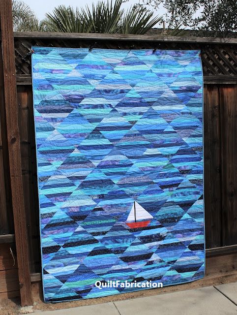 a blue quilt with a sailboat on it