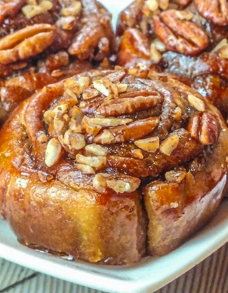 cinnamon buns with pecans on top in a white dish