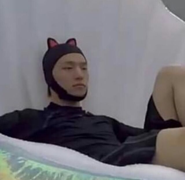 a man wearing a cat hat is laying down