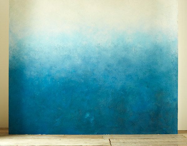 an empty room with blue and white paint on the wall, in front of a wooden floor