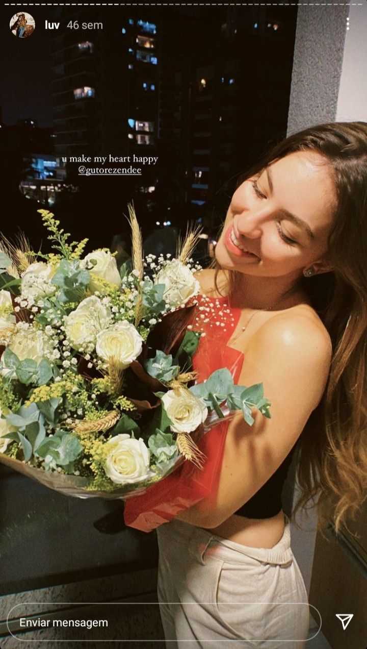 a woman holding a bouquet of flowers in front of a cityscape at night