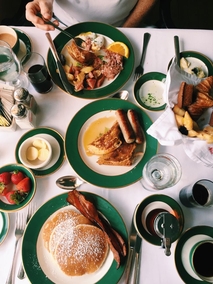 a table topped with plates and bowls filled with breakfast foods next to glasses of water