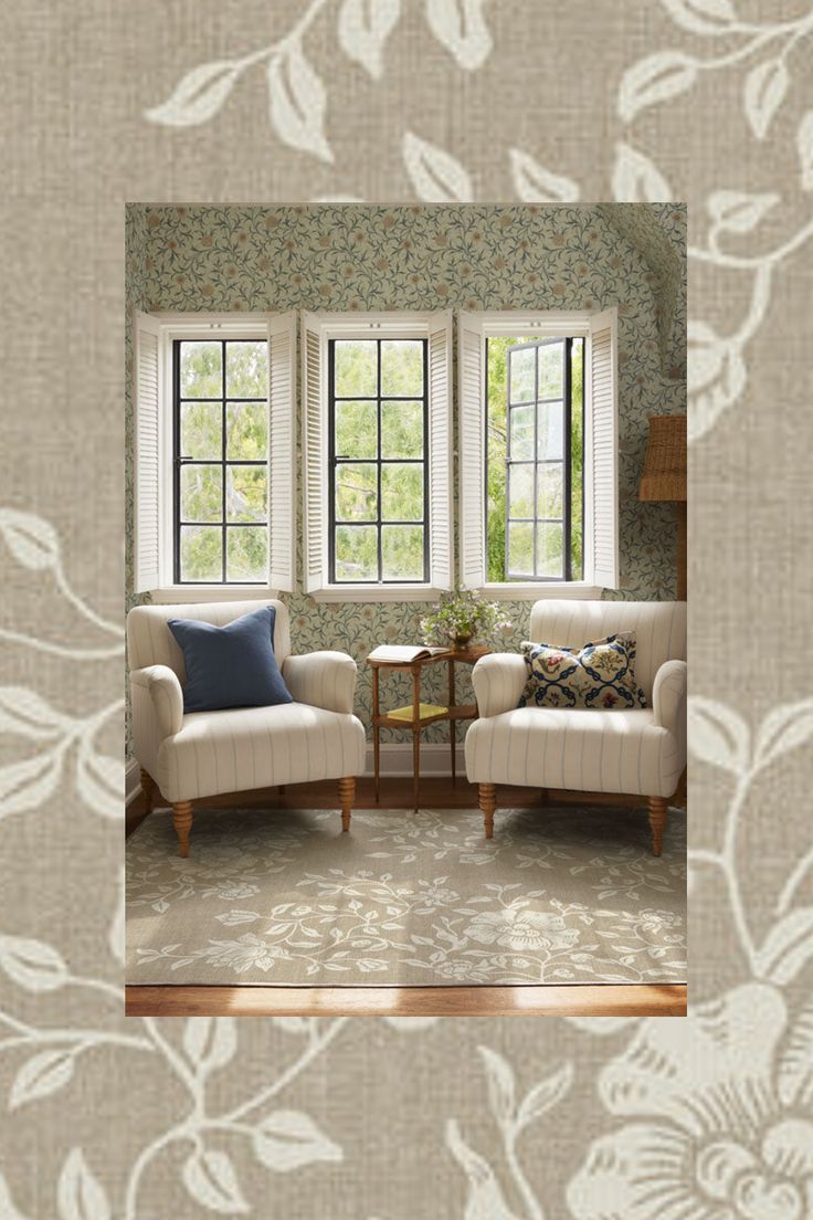 two chairs and a table in front of a window with floral wallpaper on it