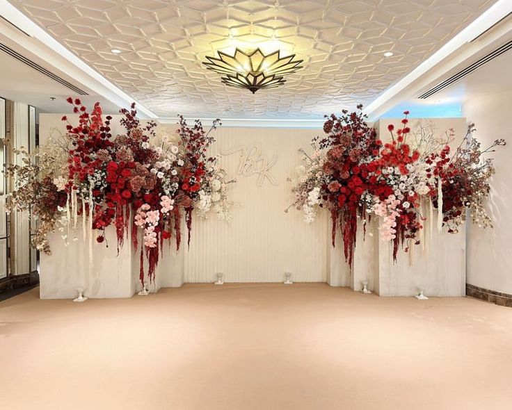 two tall vases filled with red flowers sitting on top of a white tablecloth covered floor