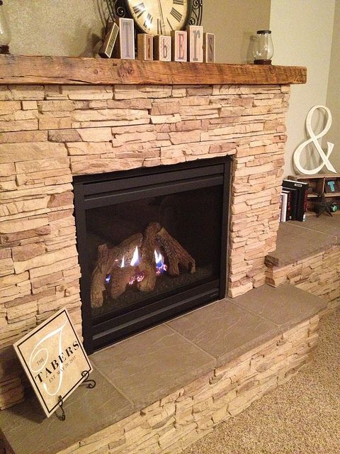 a stone fireplace with a clock on the mantle