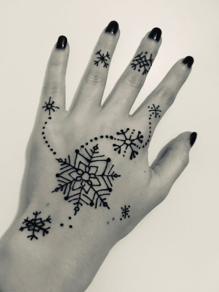 a woman's hand with snowflakes and stars tattooed on the middle of it