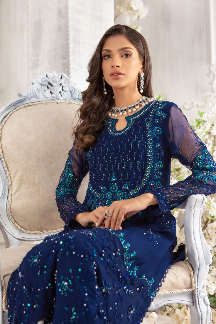 Simple paneled A-line chiffon ensemble, in stunning deep blue hue, featuring botanical embroidery on neckline, hem and sleeves, starburst sequin motifs all over shirt, dazzling sequin and crystals glistening neckline and sleeves. Eye Let embroidery border and pearls dangling’s complete the look. This stunning shirt is paired with straight pant and color-block dupatta featuring floral embroidery borders and trimmed with lace. A wardrobe must have. Shirt & dupatta Fabric: Pure Chiffon Shirt Length Party Sets With Embroidered Neckline For Eid, Festive Party Sets With Embroidered Neckline, Elegant Blue Sets With Sequins, Blue Long Sleeve Party Dress, Elegant Party Sets With Embroidered Neckline, Blue Party Dupatta With Lace Work, Blue Sequined Dress For Eid, Blue Embellished Sets In Georgette, Blue Embellished Party Kurta