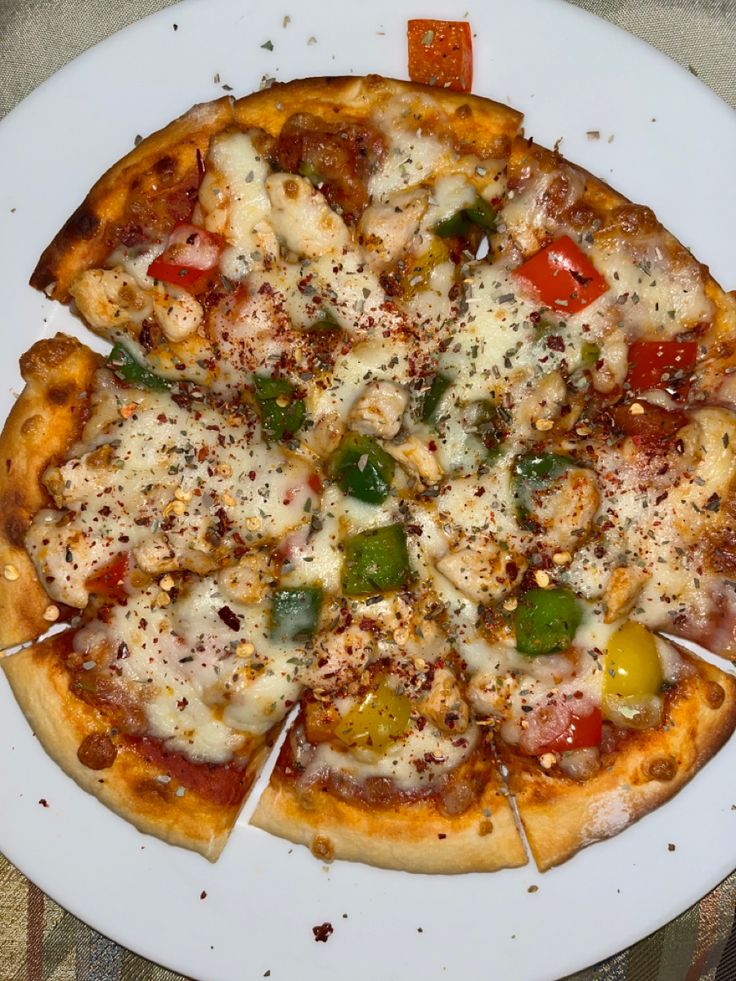 a white plate topped with a pizza covered in cheese and veggie toppings