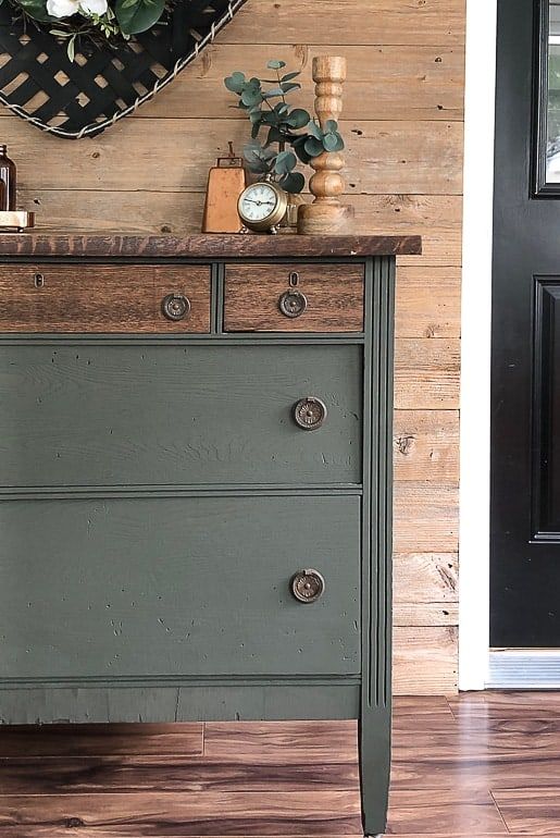 an old dresser is painted green and has some flowers on the top, along with other items