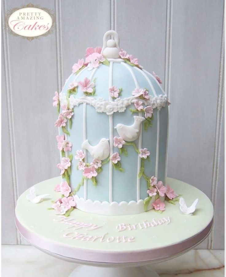 a birthday cake decorated with birds in a birdcage