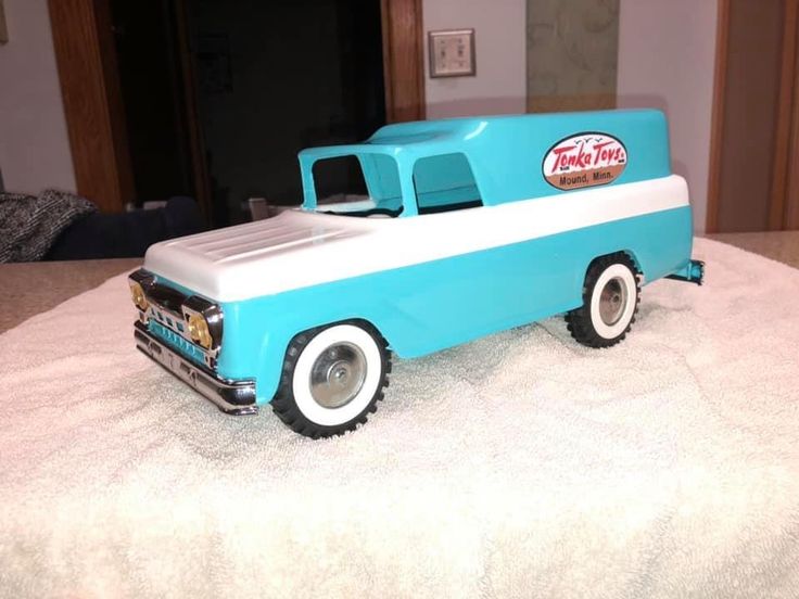 a blue and white toy truck sitting on top of a bed