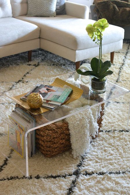 a living room with a couch, coffee table and rug on the floor in front of it