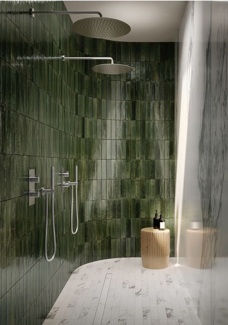 a bathroom with green tiles on the wall and shower head in the corner, along with a wooden stool