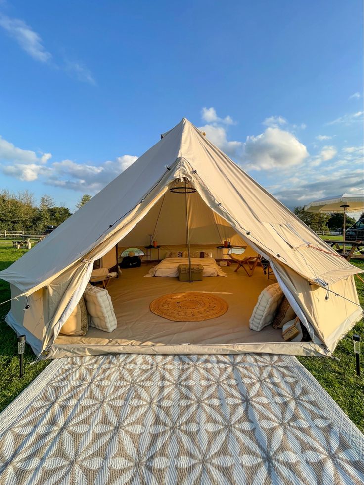 a tent set up in the middle of a field with pillows and blankets on it